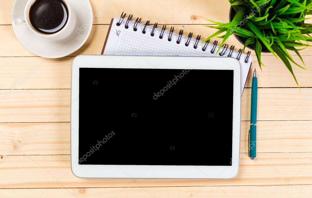 Tablet, notepad, computer and coffee cup on office wooden table