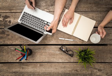 Ahşap bir masada çalışan insanlar.