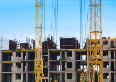 Mavi gökyüzüne karşı vinç ve inşaat alanı