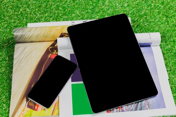 Notebook em branco, telefone na grama verde — Fotografia de Stock