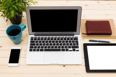 Ofis işyeri açık dizüstü bilgisayar, tablet pc, telefon ve ahşap masa kahve