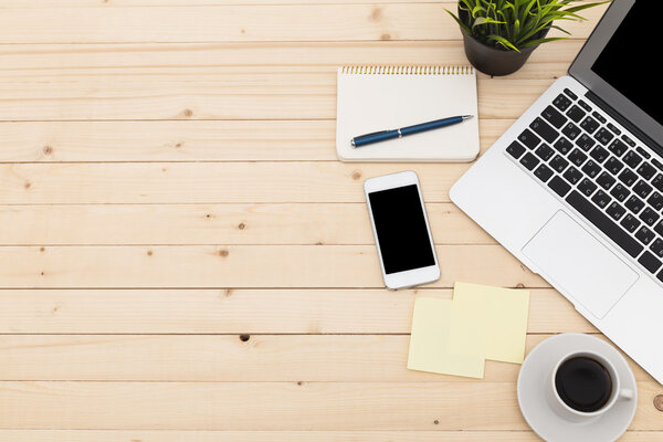 Office workplace with open laptop, tablet pc, phone and cup of coffee on wooden desk