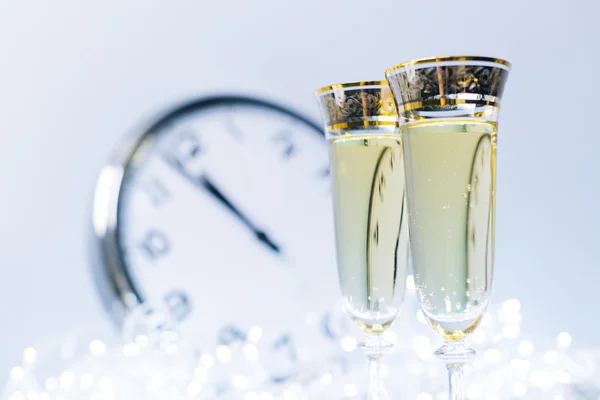 Archiwalne zdjęcie okularów z szampana przed świąteczne światełka i zegar blisko północy — Zdjęcie stockowe