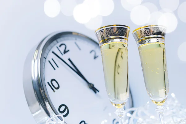Archiwalne zdjęcie okularów z szampana przed świąteczne światełka i zegar blisko północy — Zdjęcie stockowe