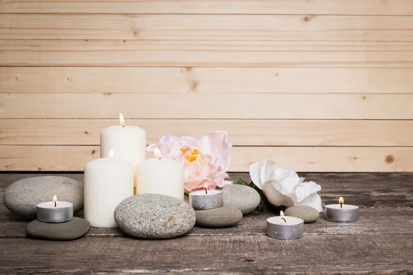 Candle and stones on wooden background — Stock Photo, Image