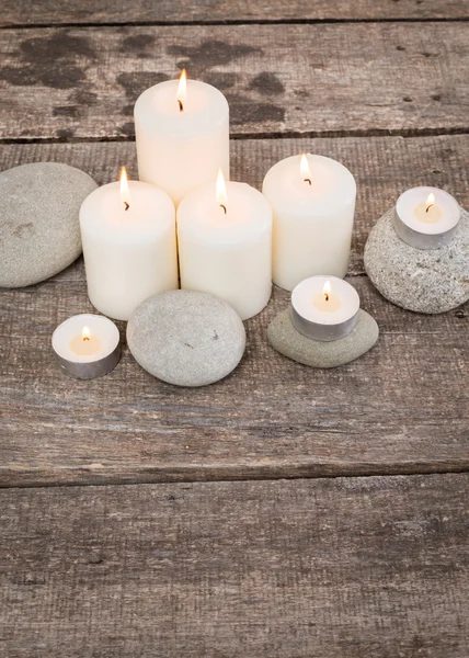 Свечи и камни на деревянном фоне — стоковое фото