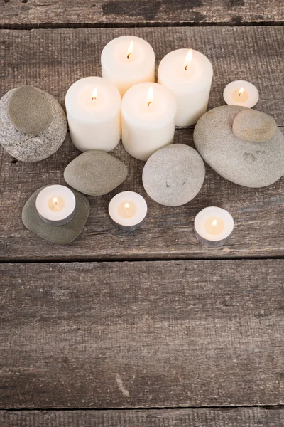 Candle and stones on wooden background — Stock Photo, Image