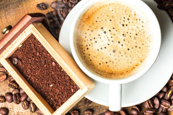 Xícara de café e grãos de café na mesa — Fotografia de Stock