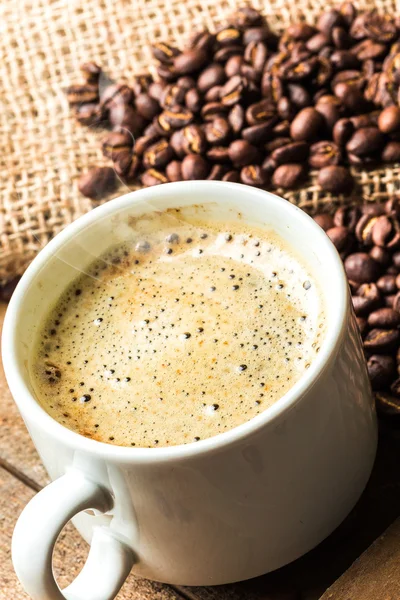 Taza de café y granos de café en la mesa —  Fotos de Stock