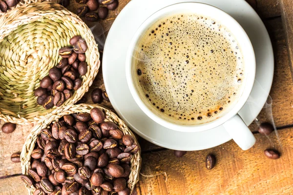 Taza de café y granos de café en la mesa — Foto de Stock
