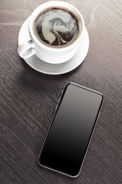 Bir fincan dekore edilmiş kapuçino ve akıllı telefon