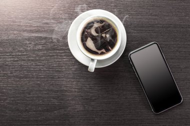 Bir fincan dekore edilmiş kapuçino ve akıllı telefon