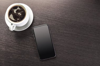 Bir fincan dekore edilmiş kapuçino ve akıllı telefon