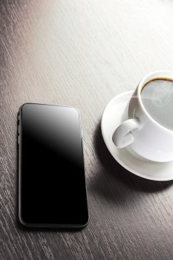 Bir fincan dekore edilmiş kapuçino ve akıllı telefon