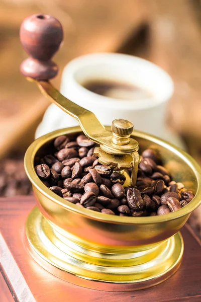 Cup of steaming hot coffee with coffee beans, coffee grinder, and coffee beans bag — Stock Photo, Image