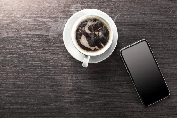 Een kopje ingerichte cappuccino en slimme telefoon — Stockfoto