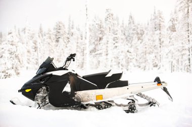 Beyaz kar aracı, kış manzarasının arka planında karlı bir arazide duruyor..