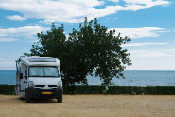 Travel trailer camper van parked at a beautiful camping with seaside coastline view.