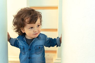 Gülümseyen uzun saçlı, beyaz bir arka plana bakan modern bir çocuğun yakın portresi.