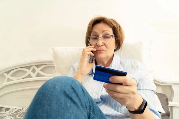 Senior Woman Frustrated Talking Mobile Phone Indoors Looking Bank Card — Stock Photo, Image