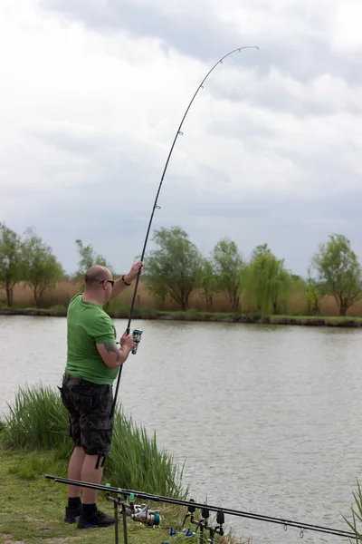 Visser in actie, visser holding staaf in de actie jonge man visserij op een meer — Stockfoto