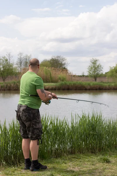 Visser in actie, visser holding staaf in de actie jonge man visserij op een meer — Stockfoto