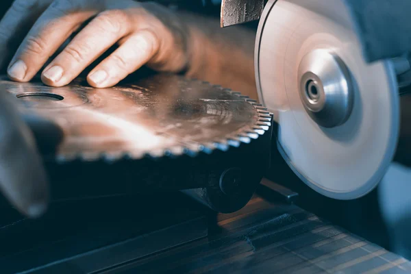 Skärpning cirkelsåg, skärper arbetaren ett cirkulär sågblad — Stockfoto