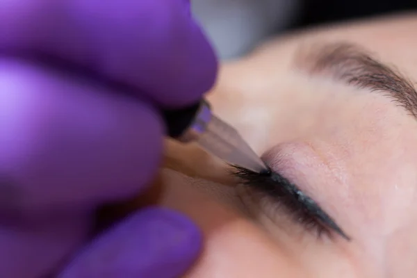 Cosmetólogo aplicando maquillaje permanente en los ojos Enfoque selectivo y poco profundo Profundidad de campo — Foto de Stock