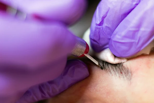 Kosmetolog tillämpa permanent makeup på ögonbrynen selektiv inriktning och kort skärpedjup — Stockfoto