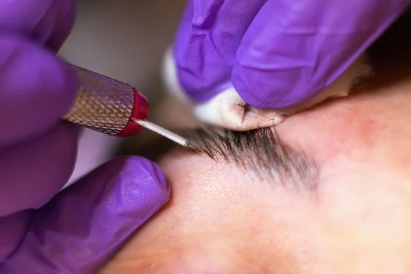 Kosmetolog tillämpa permanent makeup på ögonbrynen selektiv inriktning och kort skärpedjup — Stockfoto