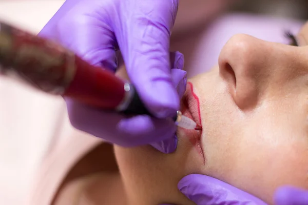 Cosmetólogo aplicando maquillaje permanente en los labios Enfoque selectivo y poco profundo Profundidad de campo — Foto de Stock