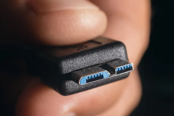 Cavo micro USB 3.0 nero. La mano dell'uomo tiene un connettore USB. Primo piano uomo mano tenendo cavo USB.Focus selettivo e superficiale Profondità di campo . — Foto Stock