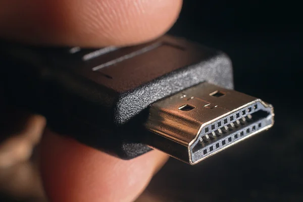 Mão segurando cabo HDMI preto. A mão do homem segura um conector HDMI. Fechar cabo HDMI. Foco seletivo e profundidade de campo rasa . — Fotografia de Stock