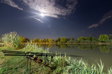 Sazan iplik makarası pod ayakta üzerinde çubuklar olta balıkçılığı. Gece balık, sazan çubuklar, cennet tam göl üzerinde ay.