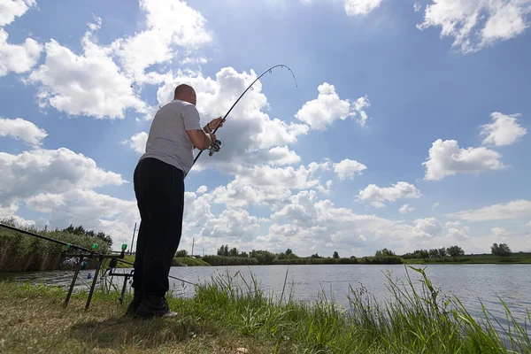 Junger Mann angelt, Fischer hält Rute in Aktion, Angler hält Rute in Aktion — Stockfoto