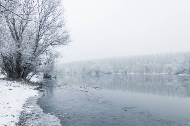 Kış gölü sahnesi suda yansıyor.