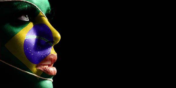 Brazil flag painted on a face of a young woman, national flag on face