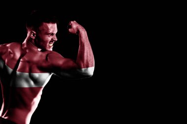 Yakışıklı, genç, kaslı adamın siyah arka planında Letonya bayrağı