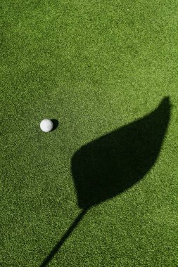 Yeşilde golf topu, yeşilde bayrağın gölgesi, golf sahası