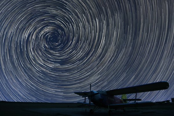 Beautiful night sky, Spiral Star trails over small airport lonely airplane. Vortex Star trails.