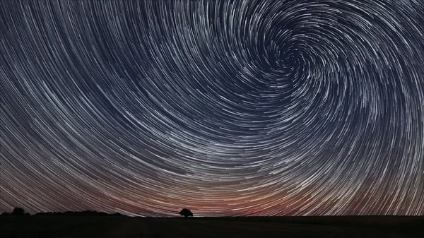 Hermosa espiral Star Trails sobre archivado con el árbol solitario. Hermoso cielo nocturno . — Foto de Stock