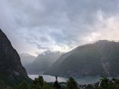 Görkemli fiyort dağları, bulutlu gökyüzü ve göl