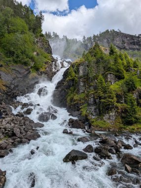 Bulutlu gökyüzü, dolambaçlı nehir, kayalık dağ zirvesi, yemyeşil orman.