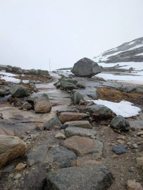Karla kaplı kayalık dağlar gri sisli gökyüzünün altında zemin.