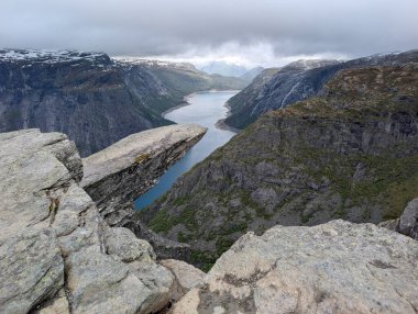 Dolambaçlı mavi nehir vadisi olan fiyort bulutlu gökyüzünün altındaki yüksek kayalık platodan izleniyor..