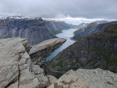 Dolambaçlı mavi nehir vadisi olan fiyort bulutlu gökyüzünün altındaki yüksek kayalık platodan izleniyor..
