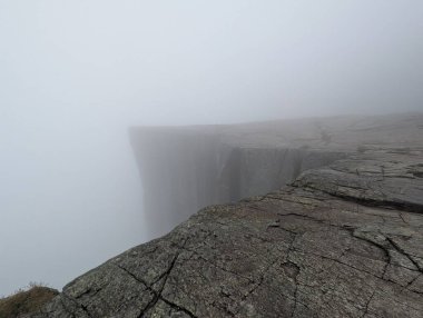Yoğun siste kaybolan kayalık kenar.
