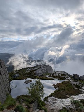 Yüksek açılı manzara, bulutlu bir gökyüzünü yansıtan küçük, sakin bir su havuzunu ortaya çıkarır..