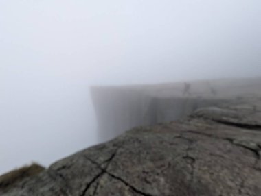 Yoğun siste bir dağın tepesinde bir insanın silueti..