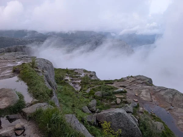Vadinin üzerindeki kayalık uçurumlar ve bulutlarla puslu dağ manzarası.
